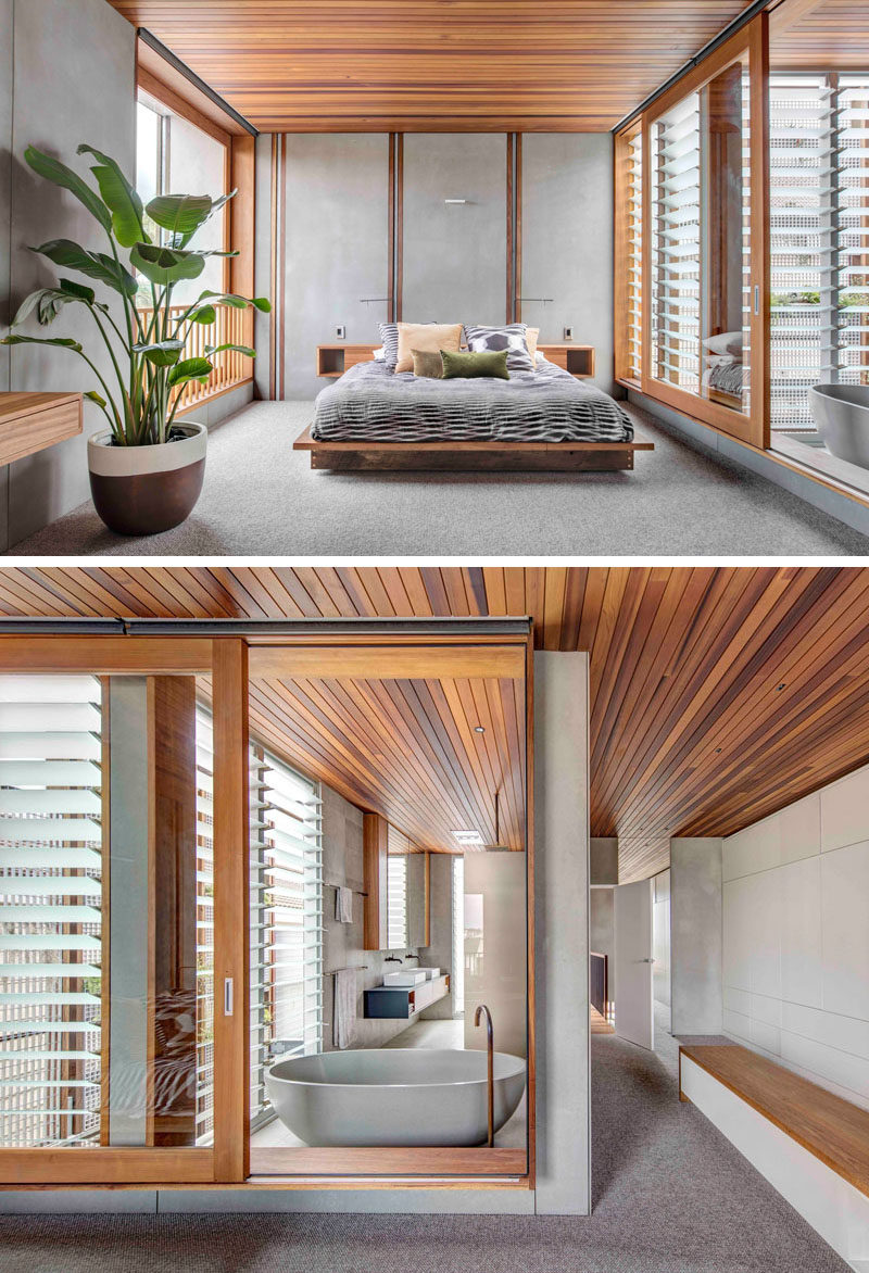 This master bedroom, minimal in its design, has large walls of windows that open to let a cross breeze through. The wood ceiling continues from the bedroom through to the ensuite bathroom that's separated with a large sliding glass window.