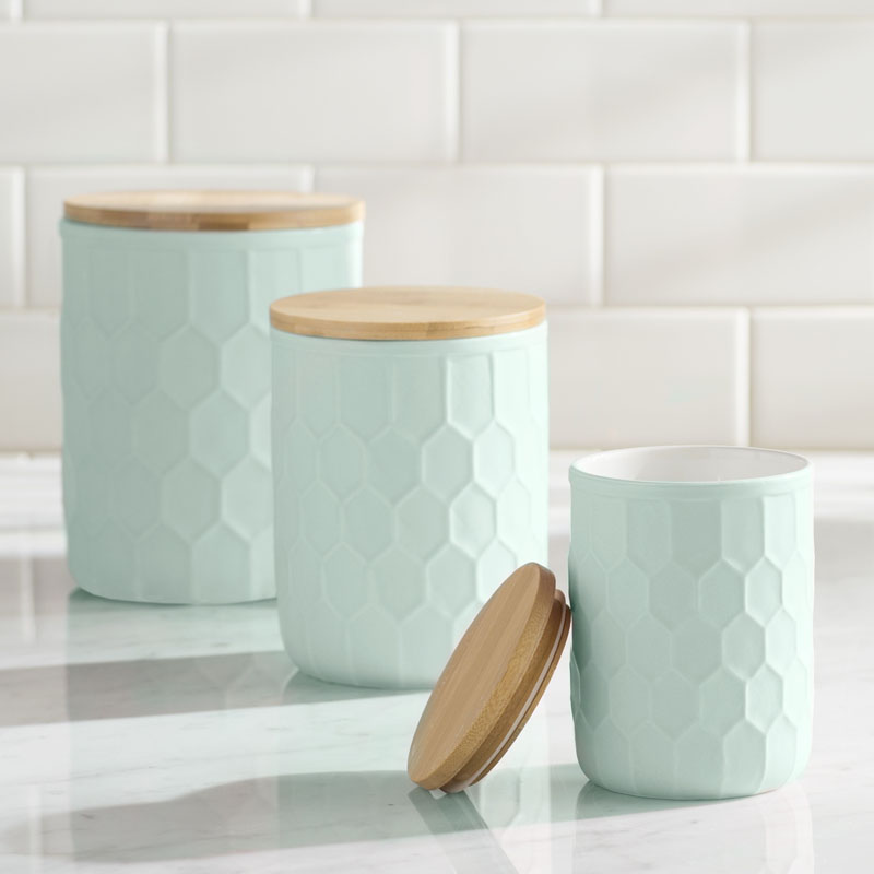 Topped with a bamboo lid to stow various goods, these modern mint colored canisters have a honeycomb inspired pattern making them easy to hold. #PantryIdeas #StorageIdeas #KitchenStorage #KitchenJars #ModernJar #ModernCanister #PantryJars