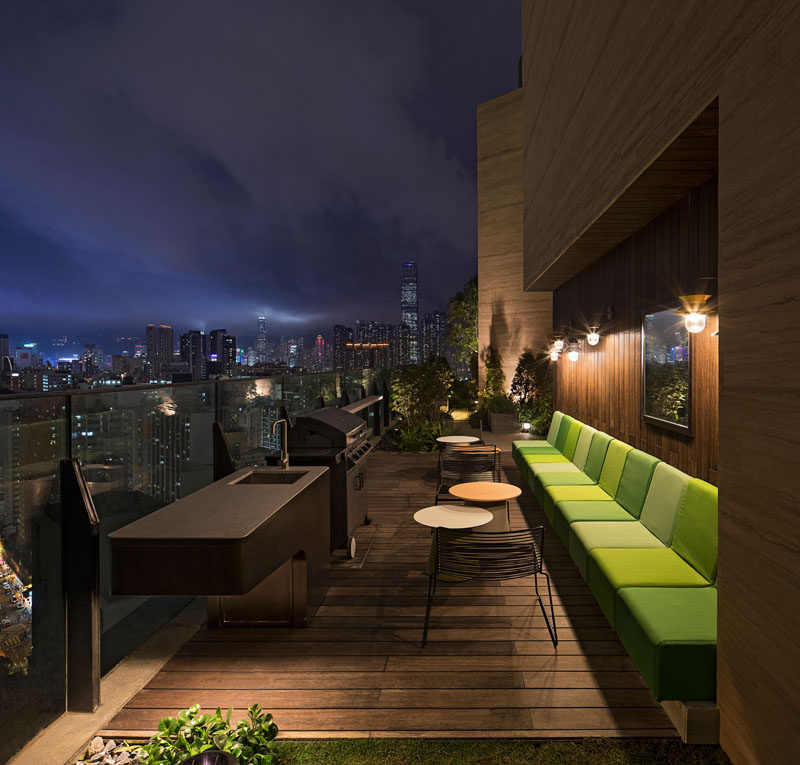 This modern residential building in Hong Kong has a barbeque area with built-in bench seating and wood accent walls.