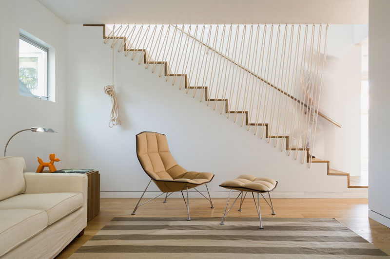 These modern stairs have a rope safety barrier along one side of the stairs and a metal railing on the other side, making sure that these white and wood stairs are safe and chic at all times.