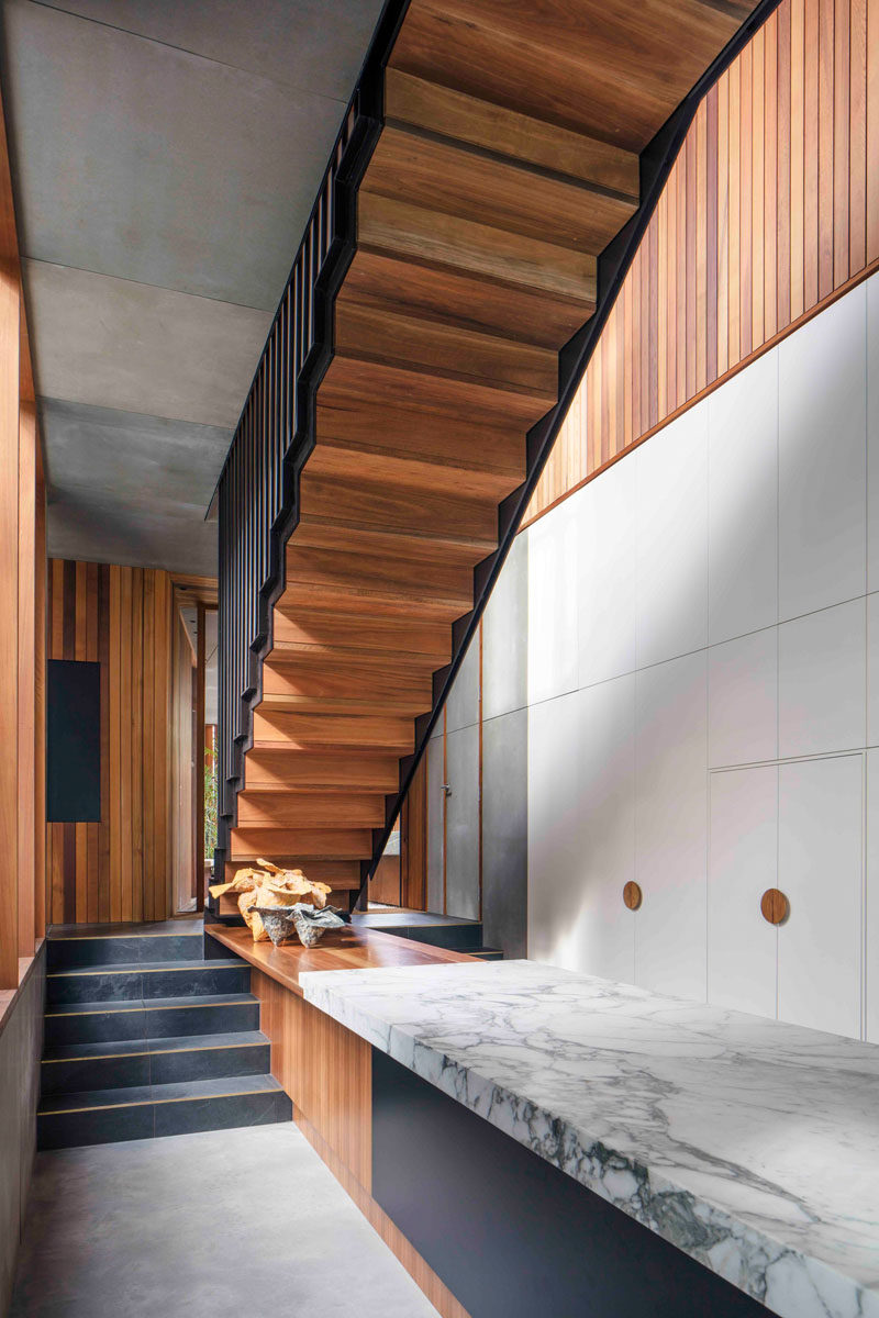 In this modern house, there are small steps that lead to the main living and dining area. A custom wood counter that meets the top of the steps is connected to the countertop on the kitchen island.