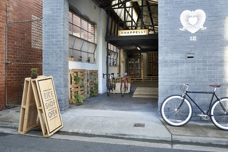 Two wood pallets have been attached with hinges and rope, and then minimally painted to create a simple wood sign letting people know that the bike shop is open.