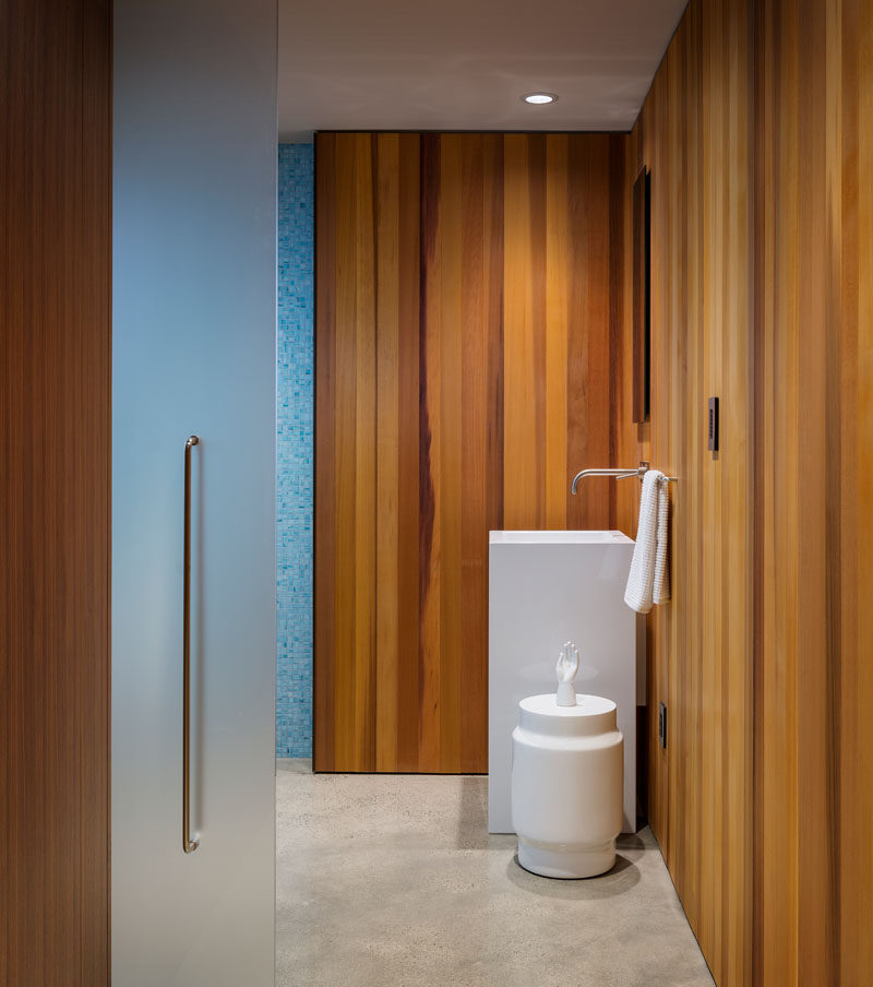 This guest bathroom has walls of cedar and a minimal white vanity.