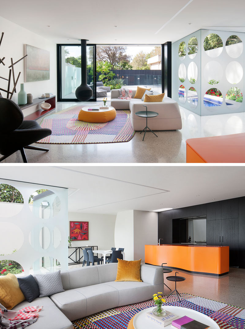 This living room opens up to the patio outside through large black-framed sliding glass doors. To tie in with the black frames, a Bathyscafocus suspended fireplace hangs from the ceiling. The living room is also open to the kitchen and the dining area.