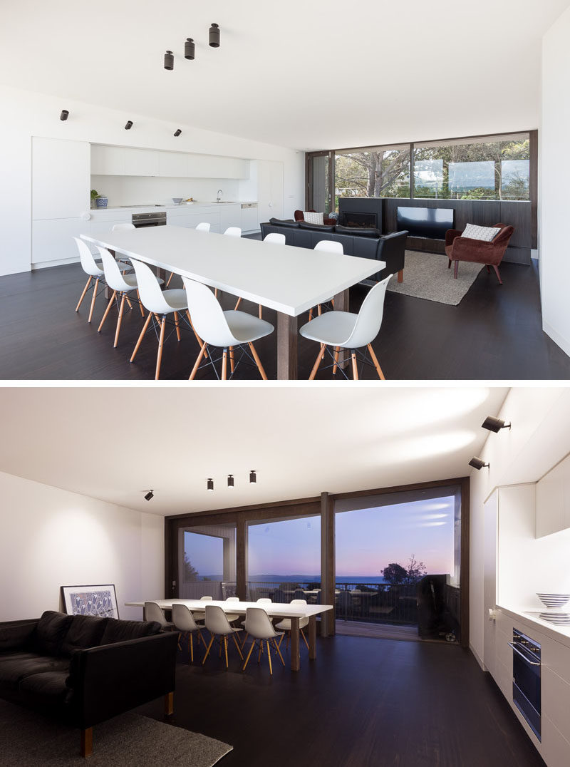 In this modern beach house, the living room and dining area share the same space, but face away from each other to create separation. The living room faces the front of the home, while the dining area faces the back of the home. The minimalist white kitchen keeps the space uncluttered and functional. 