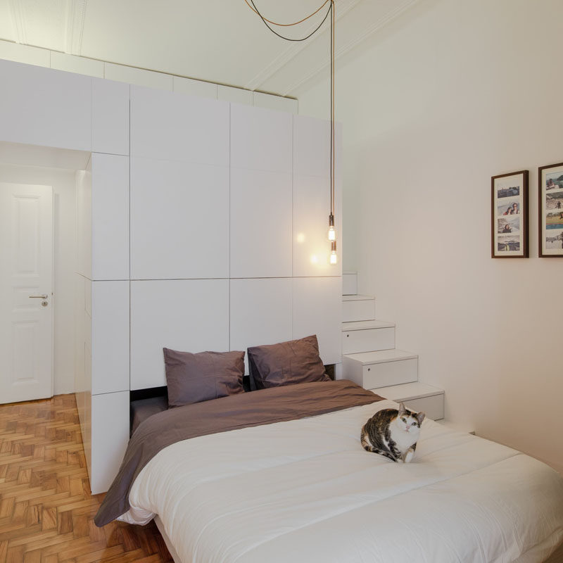 This small modern apartment has a wall of white storage cabinets that allows a pull-out bed to be hidden within it.