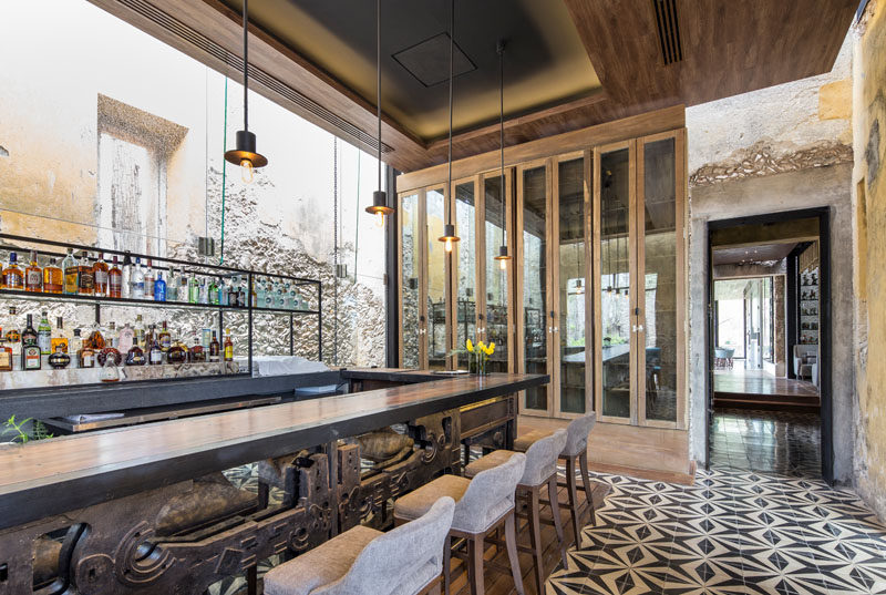 In this bar area of a restaurant inside an old farm building, original stone walls have been combined with open steel shelving and a large wood bar. A large cabinet with mirrored doors makes the room feel larger than it is.