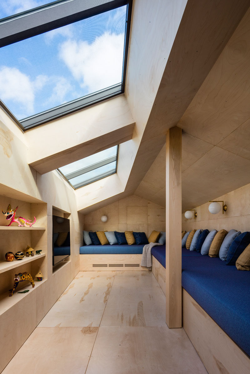 This cozy media room has plenty of skylights and built-in seating with lots of pillows. On the opposite side of the small room is a wood with sections cut-out for shelving and to house the television.