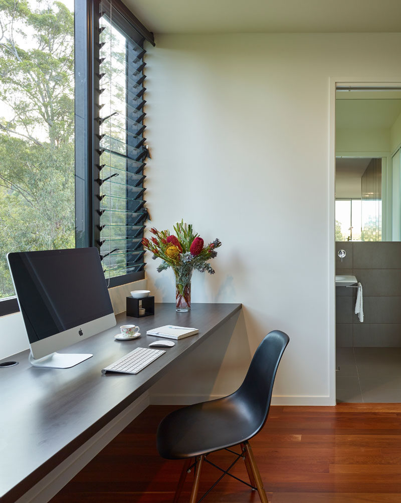 In this hallway to the bathroom, is a small home office with a floating desk. A combination of windows and louvers allows natural light to fill the space.