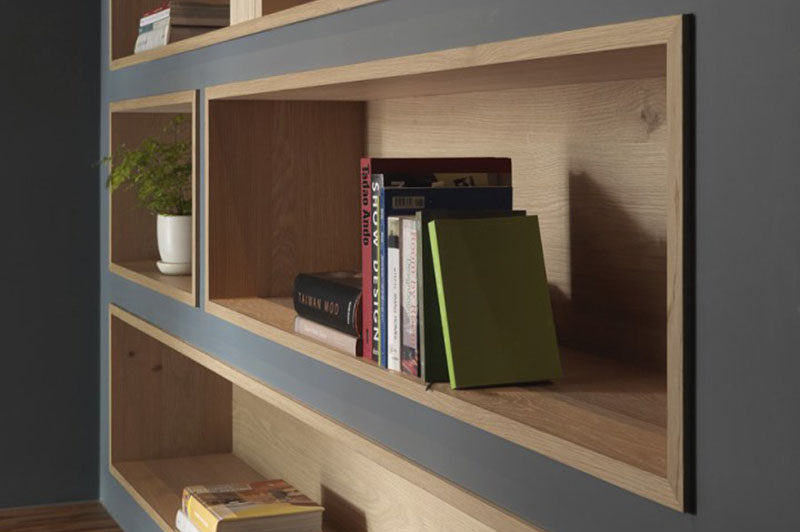 To make the built-in bookshelves on this deep grey wall stand out, the shelves were lined with wood to add a natural touch and create warmth in the office interior.