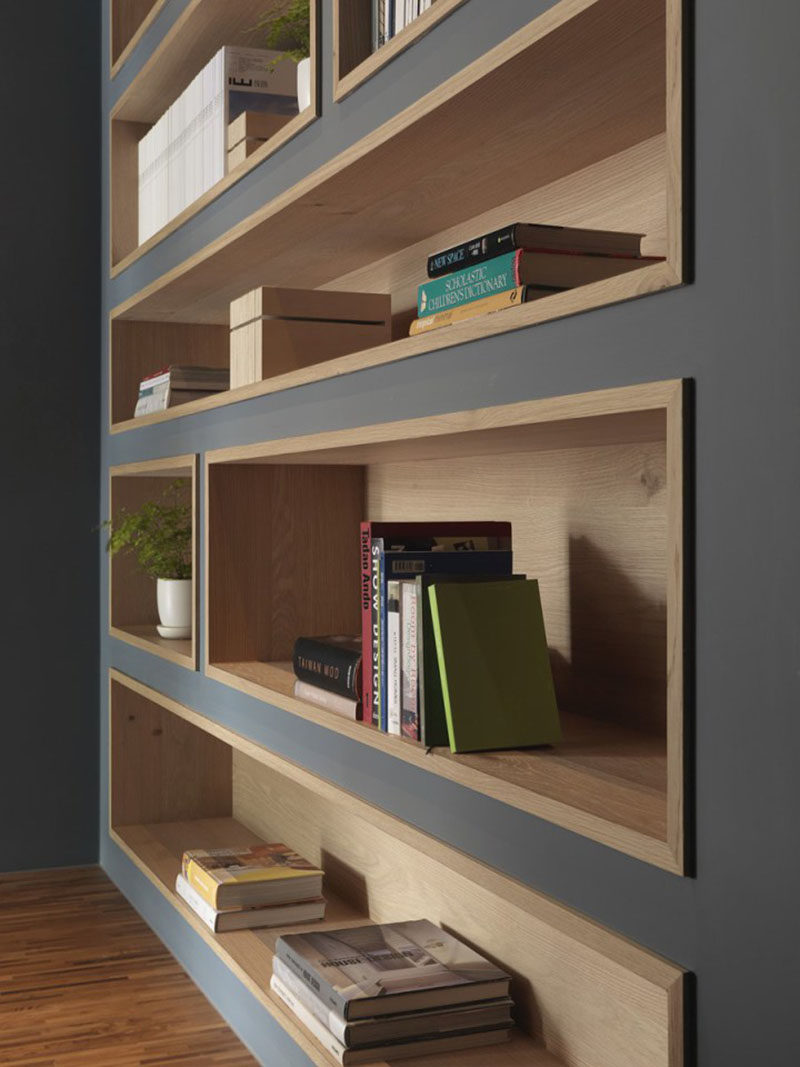 To make the built-in bookshelves on this deep grey wall stand out, the shelves were lined with wood to add a natural touch and create warmth in the office interior.