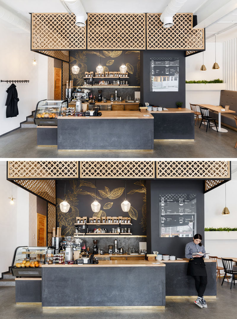 Central to this modern coffee shop is the service area with dark walls and a concrete base. Wood screens, countertops and decorative gold artwork compliments the look.