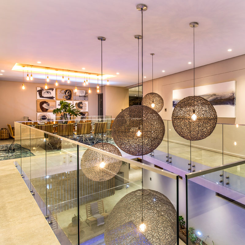 The large, round, textured pendant lights hang from the ceiling in this modern space, going all the way down to the lower area of the house where the indoor pool is.