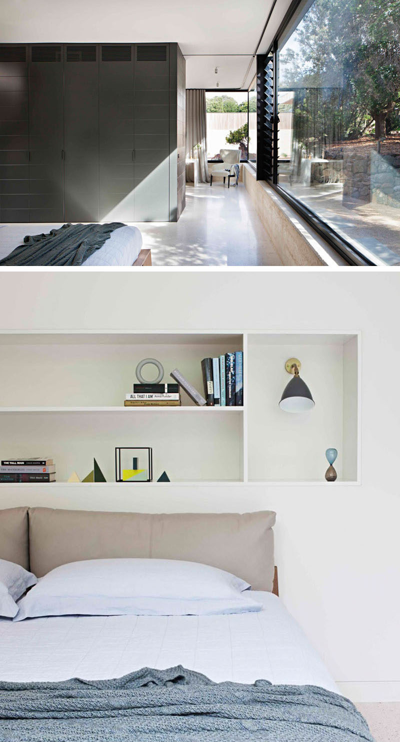 This modern bedroom is tucked around the corner from the study. It looks out to the garden and a wall of dark cabinetry lines the wall. Shelving above the bed provides a place to store favorite books and decorative elements. 