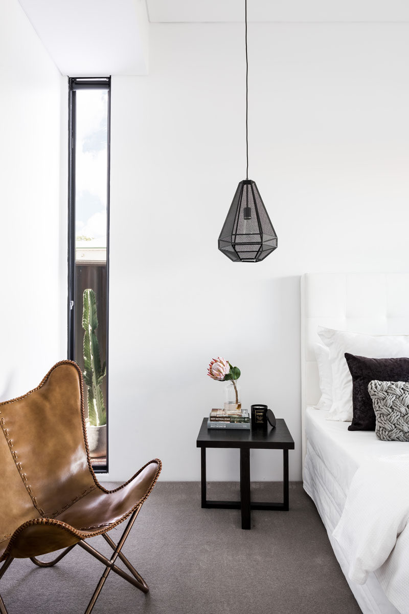 This modern master bedroom, situated at the rear of the house has a simple palette of white and grey with black accents.