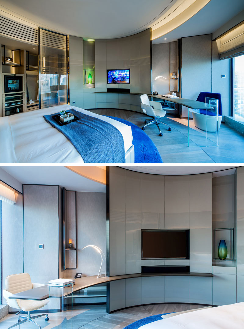 The rooms inside this modern hotel have a simple blue color palette and are minimally decorated. A curved wall with a built-in TV is a main design element, creating the effect of a circular room.