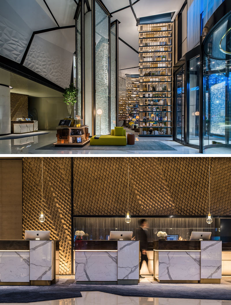 Arriving in this modern hotel lobby, a blend of materials, textures, and geometric patterns can be seen everywhere. The marble and gold front desks sit below individual pendant lights, and in front of a gold textured honeycomb wall that looks like it's moving.