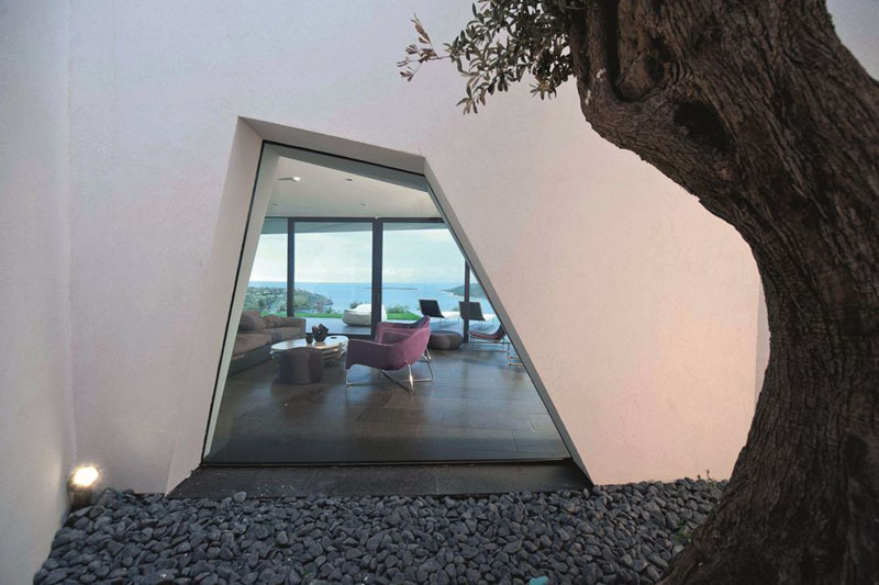 The window of this modern house is geometric in shape, and provides a ground level glimpse of the interior. 