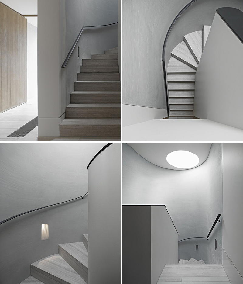 These modern curved grey stairs lead to the other levels of the home, while a circular skylight provides natural light to the stairwell.