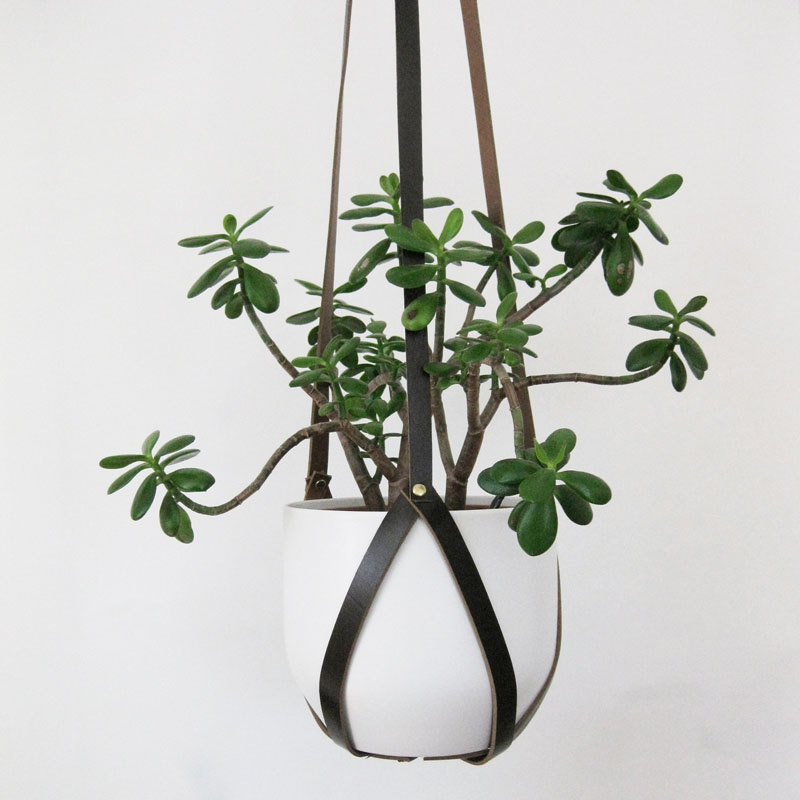 Made from recycled tan leather, this modern hanging planter is 3.5 feet (1.1m) long and has brass rivets that can be adjusted to accommodate for the size of a pot.  #HangingPlanter #ModernPlanter #HomeDecor #Garden #Plants