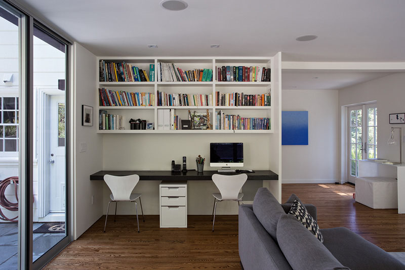 A black desk built-in below the white shelves makes this small space a functional home office for two.