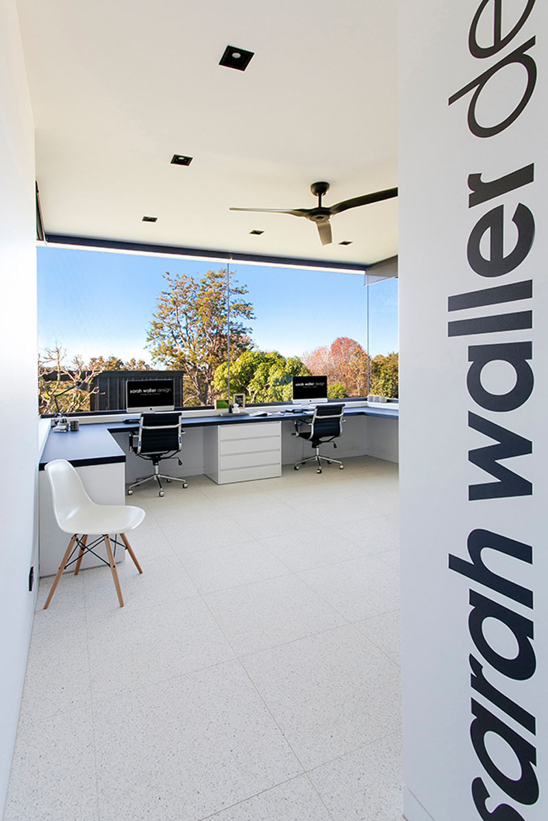 White with black accents, this modern home office has large wrap around windows allowing natural light to pour in all day.