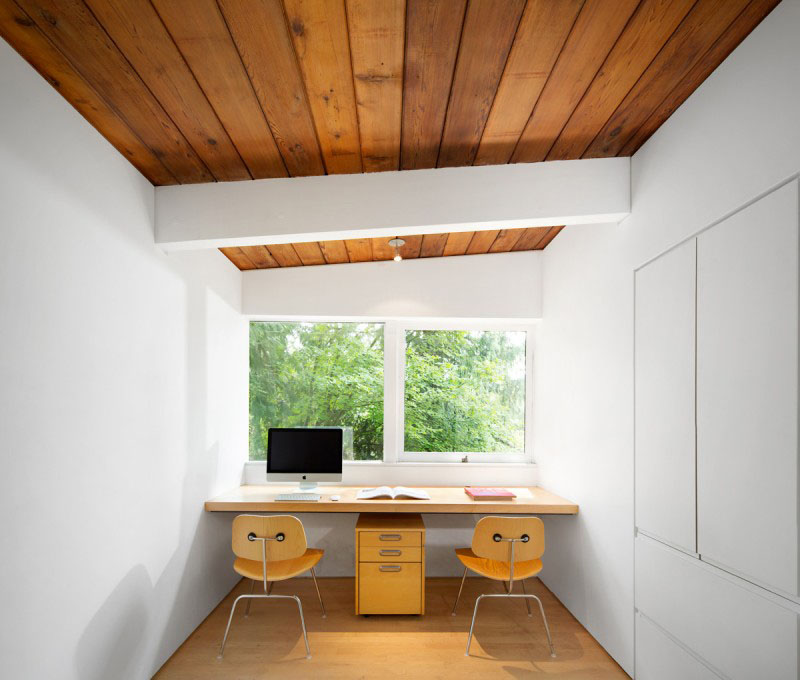 This bright white minimalist home office has a wood ceiling and floor, while a floating desk has enough room for two.