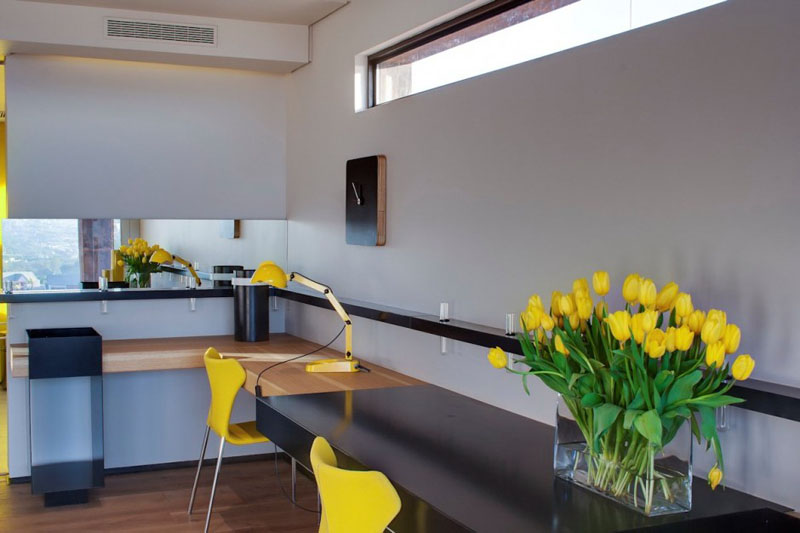  A thin window above the large corner desk, along with yellow chairs and accents, brightens up this home office for two.