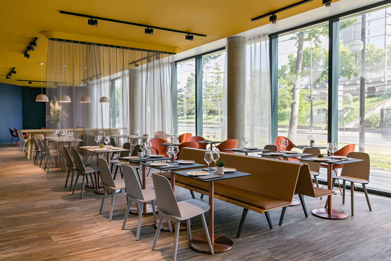 This modern hotel has an area set up for dining. Long bench seating sits back to back to create two rows of dining tables and chairs.