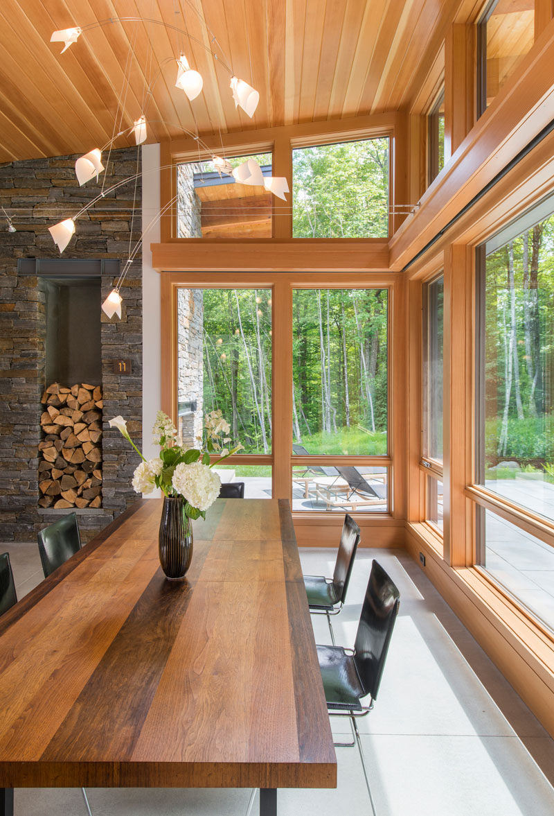 Wood framed windows provide this dining room views of the surrounding woods. A large wood table also compliments the wood ceiling and window frames.