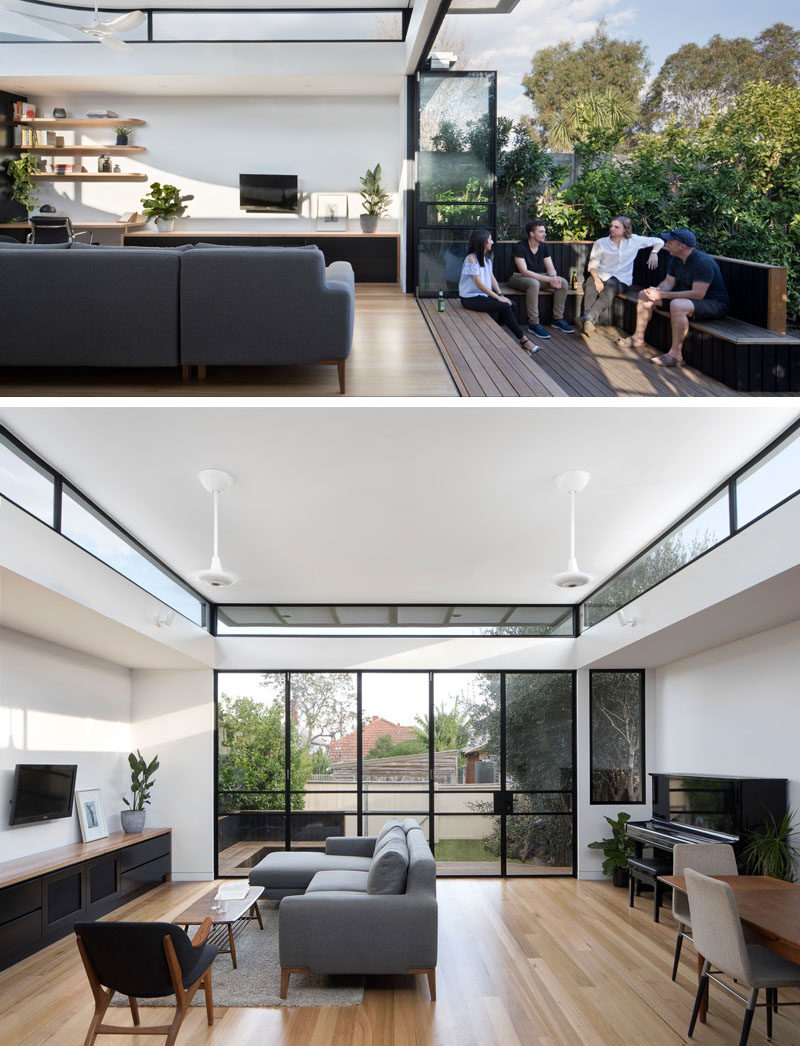 This modern house extension, which opens up to the backyard, has a wooden deck with built-in seating, with the stairs acting as an additional spot to sit. Folding black-framed doors can be closed at night, however they don't block the view of the garden as they are glass, and during the day, the sunlight can flood the interior.