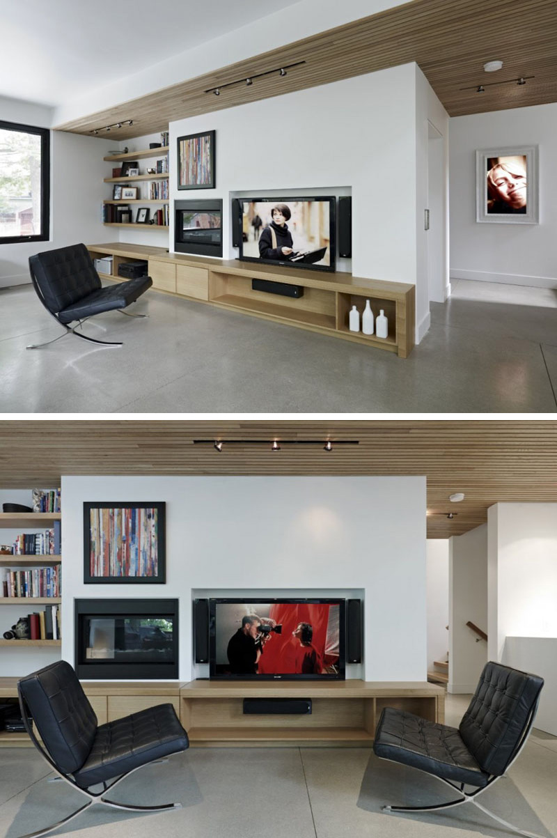 In this modern living room, built-in wood shelves, and entertainment unit compliment the wood used in ceiling. Behind the wall of the TV, is the elevator that leads to other parts of the home.