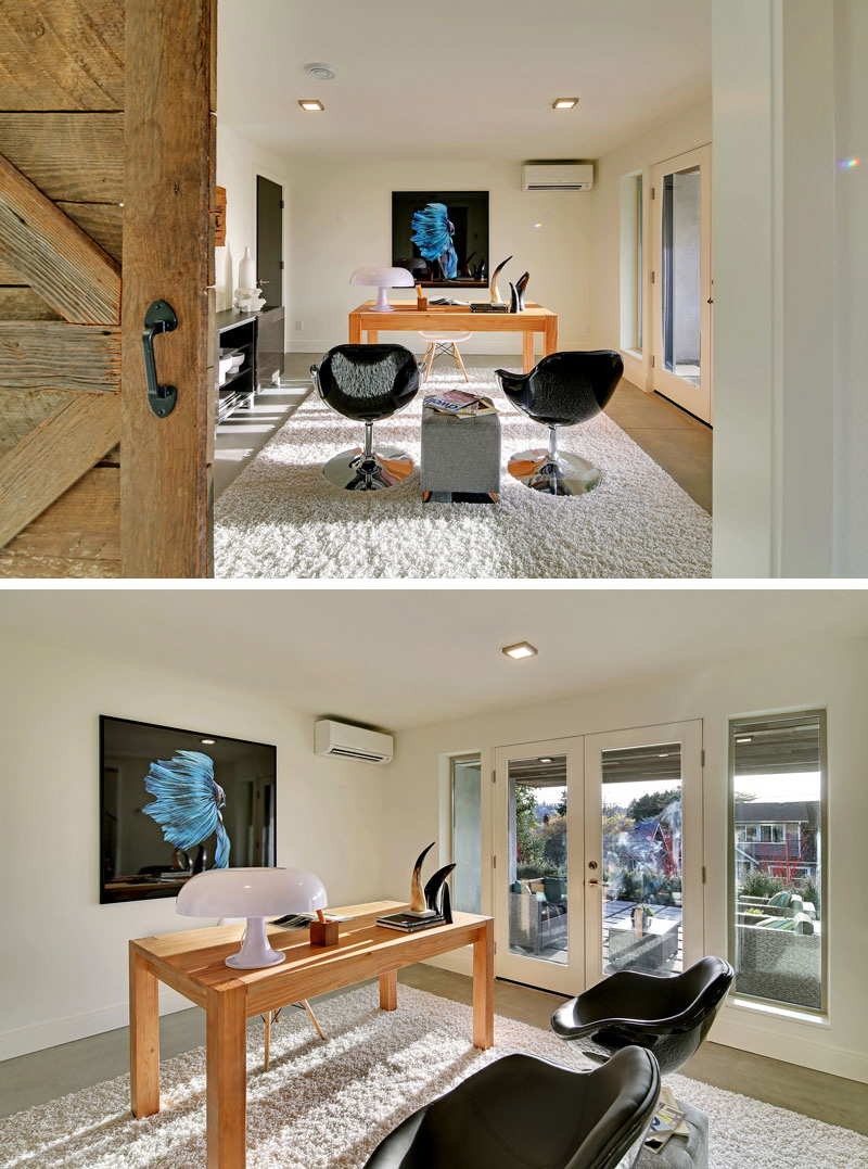 To the left of the entrance in this modern home, and through a sliding wood barn door is the home office. A set of glass, white framed doors lead to the outdoor patio by the front entrance