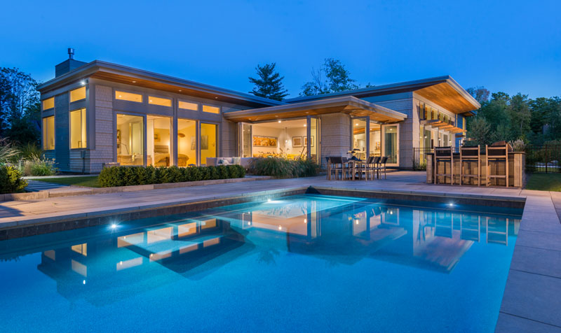 This modern house open up to a swimming pool, outdoor lounge, dining area and a bar.