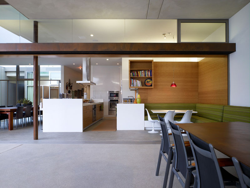 To the side of this modern kitchen is a built-in dining nook. The banquette seating continues through to the outside, with the seating only separated when the sliding glass door is closed.