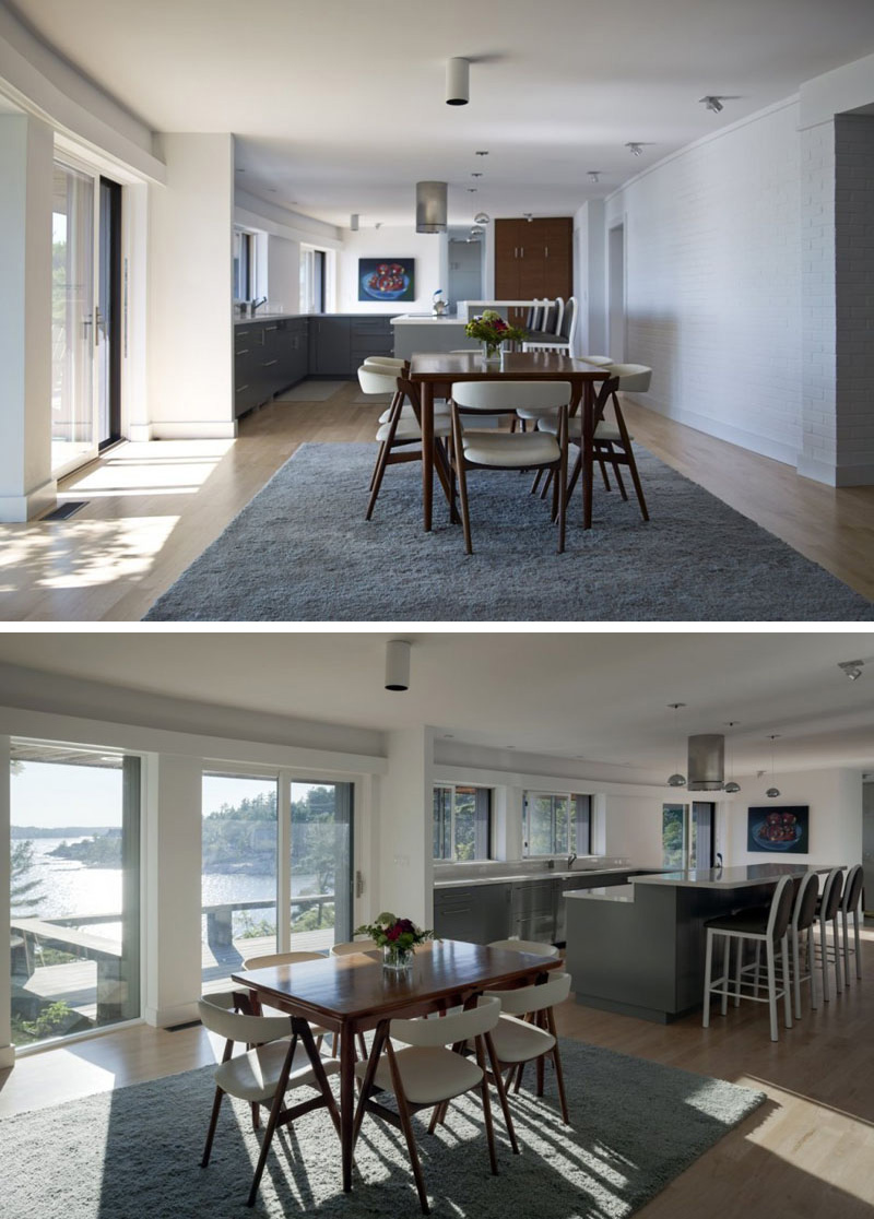 In this modern dining room, a wood dining set with white upholstered chairs is placed on top of a thick grey carpet. Sliding glass doors in front of the table provide an excellent view, and lead to the outdoor balcony.