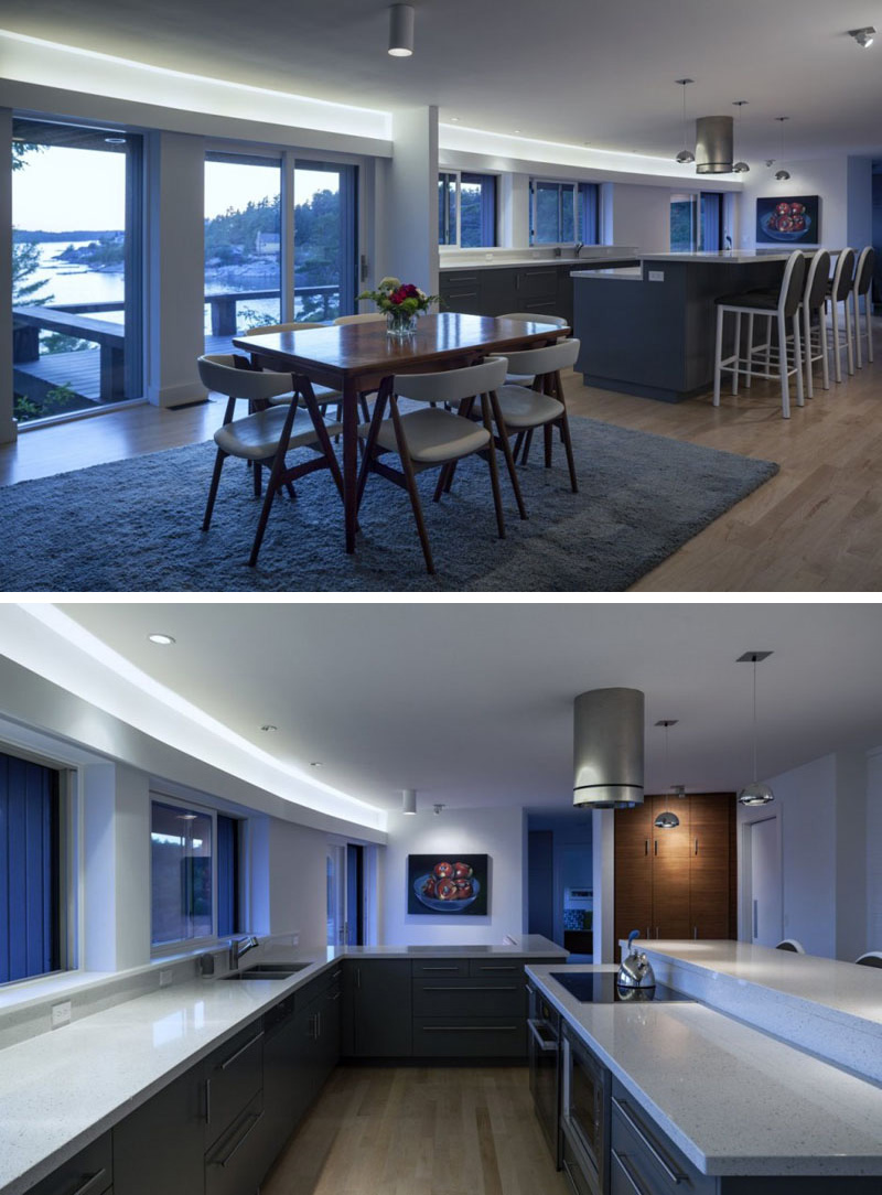 Hidden lighting above the windows and the glass balcony doors in this modern kitchen and dining area ensures that these rooms are always bright.