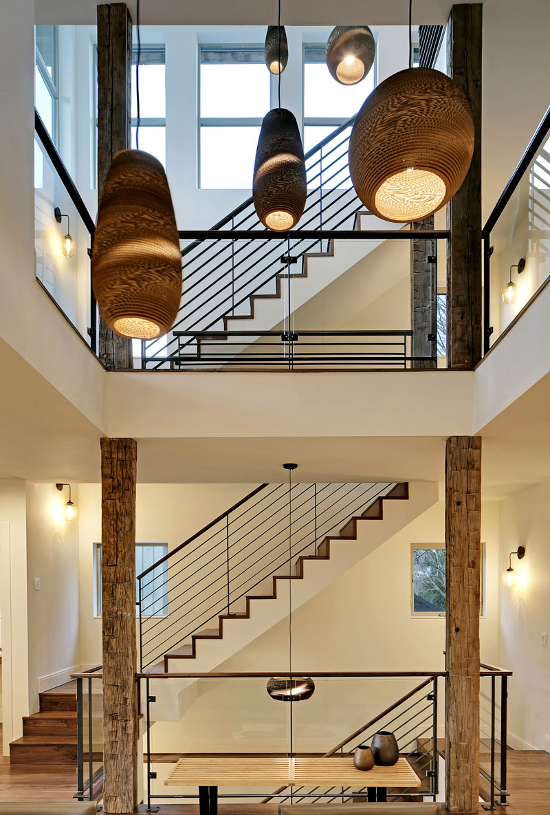 The four-storey set of stairs is situated beside an atrium in the middle of this modern home. Long, handmade pendant lights hang in the atrium filling the big open space.