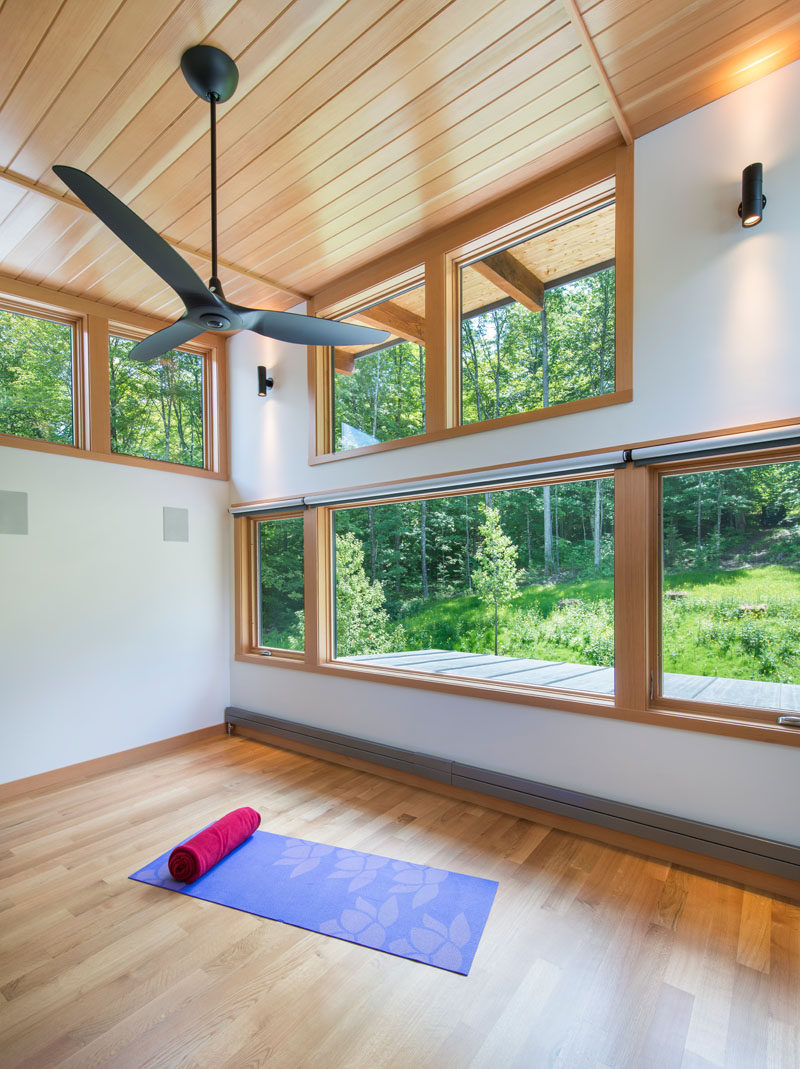 This modern house surrounded by woods, has a yoga studio with high ceilings and views of the trees.