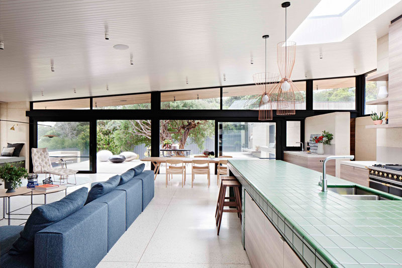 This modern house has a large main living area that's home to the living room, dining room and kitchen. A sloped roof and skylights add plenty of natural light to the room.