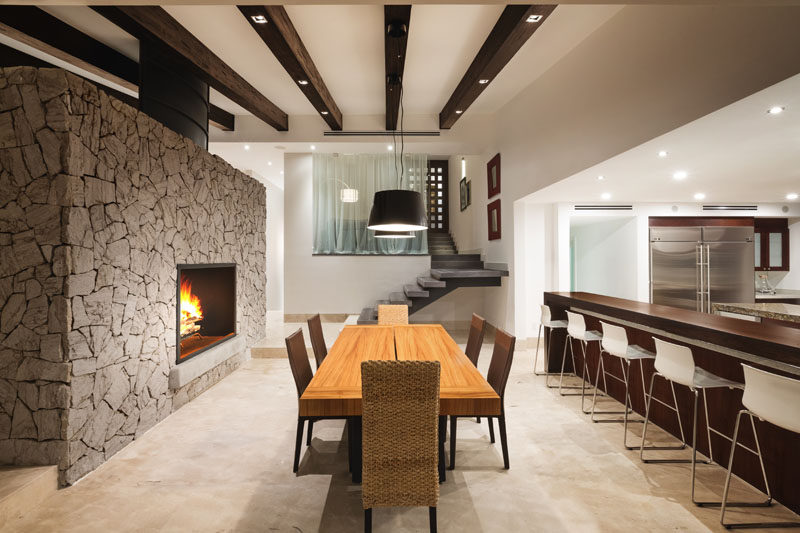 A large grey stone double-sided fireplace separates the dining room and kitchen from the living room. Large format marble sheets were used for the flooring in the main living and dining area.