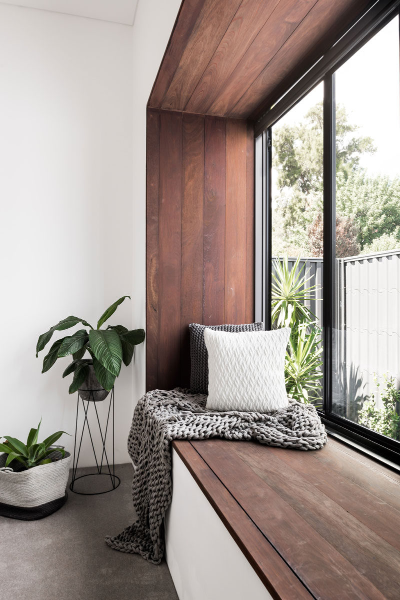 This modern bedroom has a wood framed window seat that overlooks the garden.