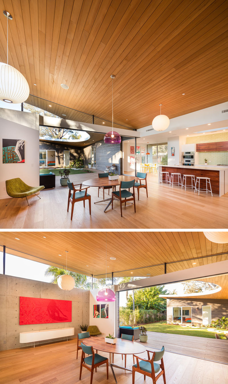 In this modern dining area, a purple glass pendant lamp hangs above the wood table with blue upholstered chairs.