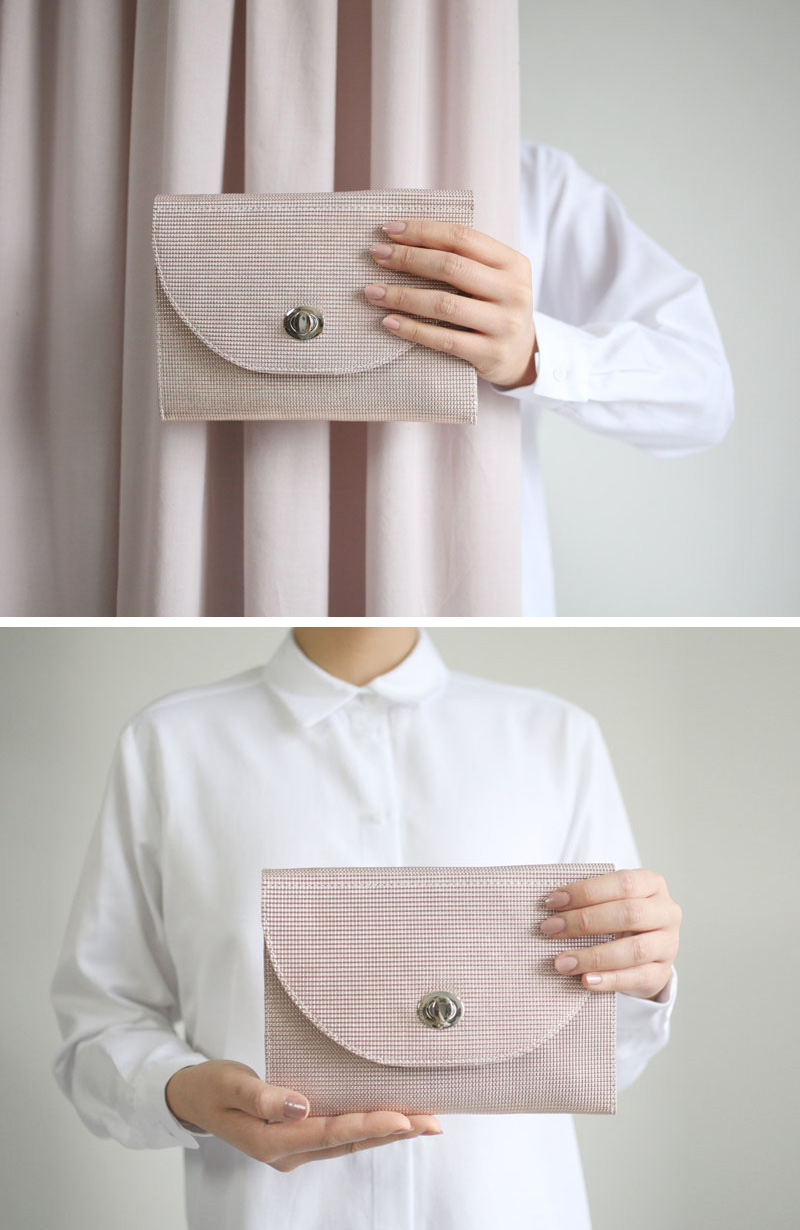 This modern leather clutch is blush in color with a textured material. 