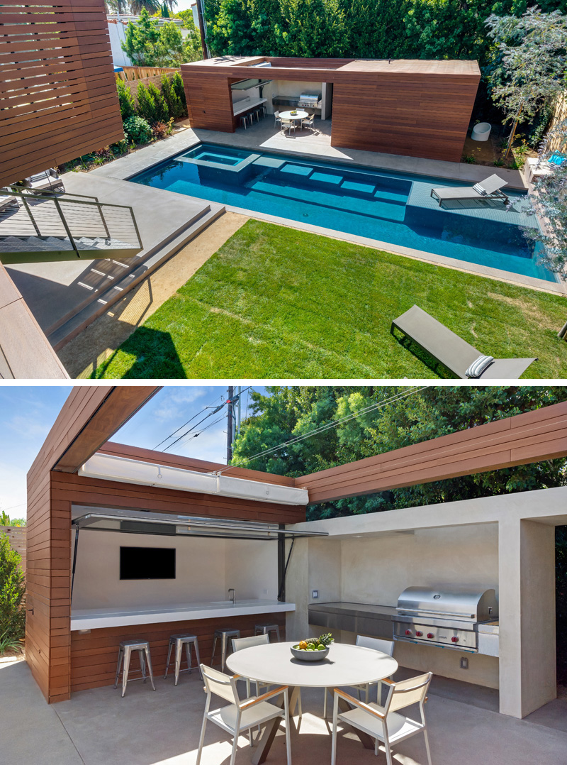 This modern wood and concrete pool house features a bar area with a TV, and a full sized BBQ. A skylight above makes this the perfect place to snack beside the pool.