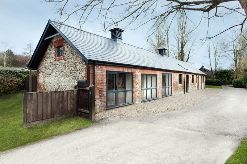 This modern stable house maintains it's unique character with the the original foundation and brick exterior. A new roof has been added for longevity, matching the large black framed windows.