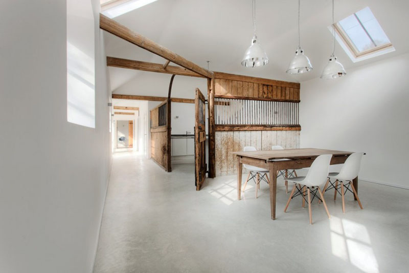 In this modern dining room, the wood dining table is anchored beneath three hanging silver pendant lights. Skylights and windows makes this already bright room, lighter.