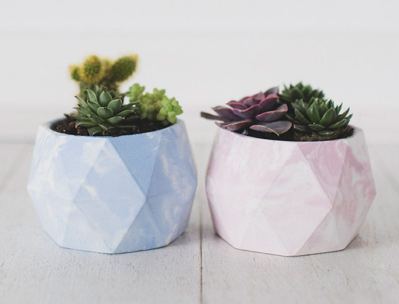 These modern concrete planters are light blue and pink with a marbled effect, and have a geometric design. 