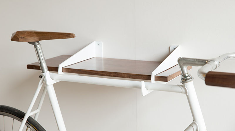 A modern white and wood shelf that doubles as a wall mounted bike rack.