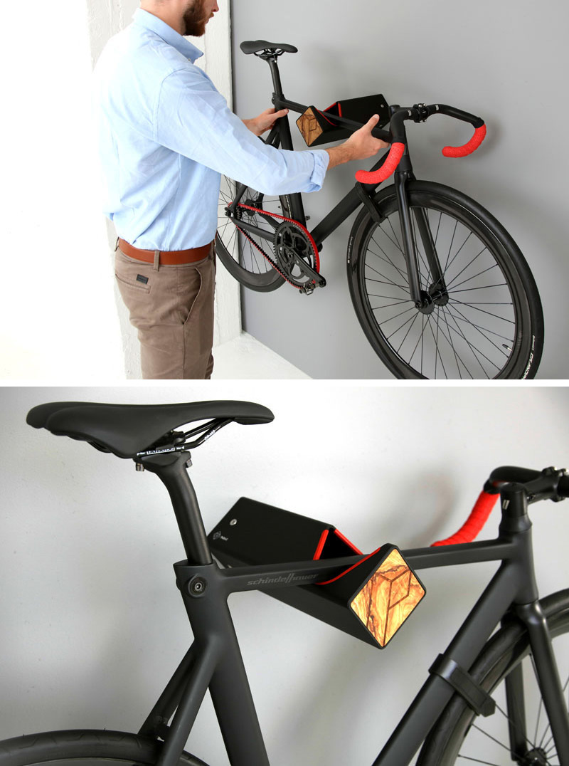 A wall mounted bike rack made from black aluminum, red silicone, and wood.
